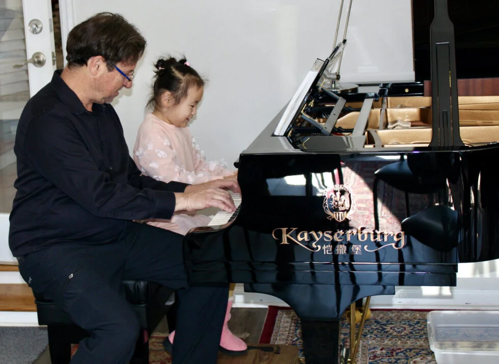 Dr. Francisco Silva at a grand piano with Hannah, age 5